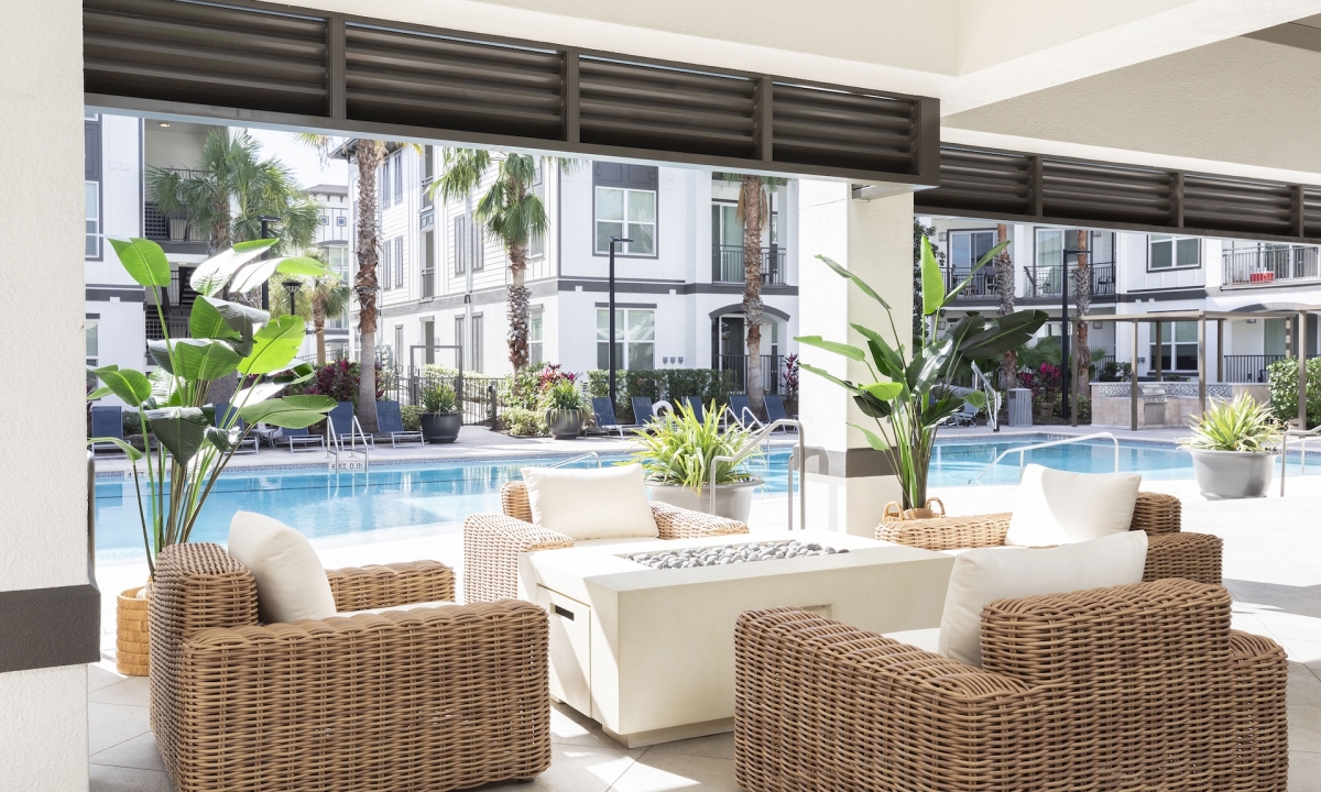 A poolside seating area with wicker furniture and a fire pit.