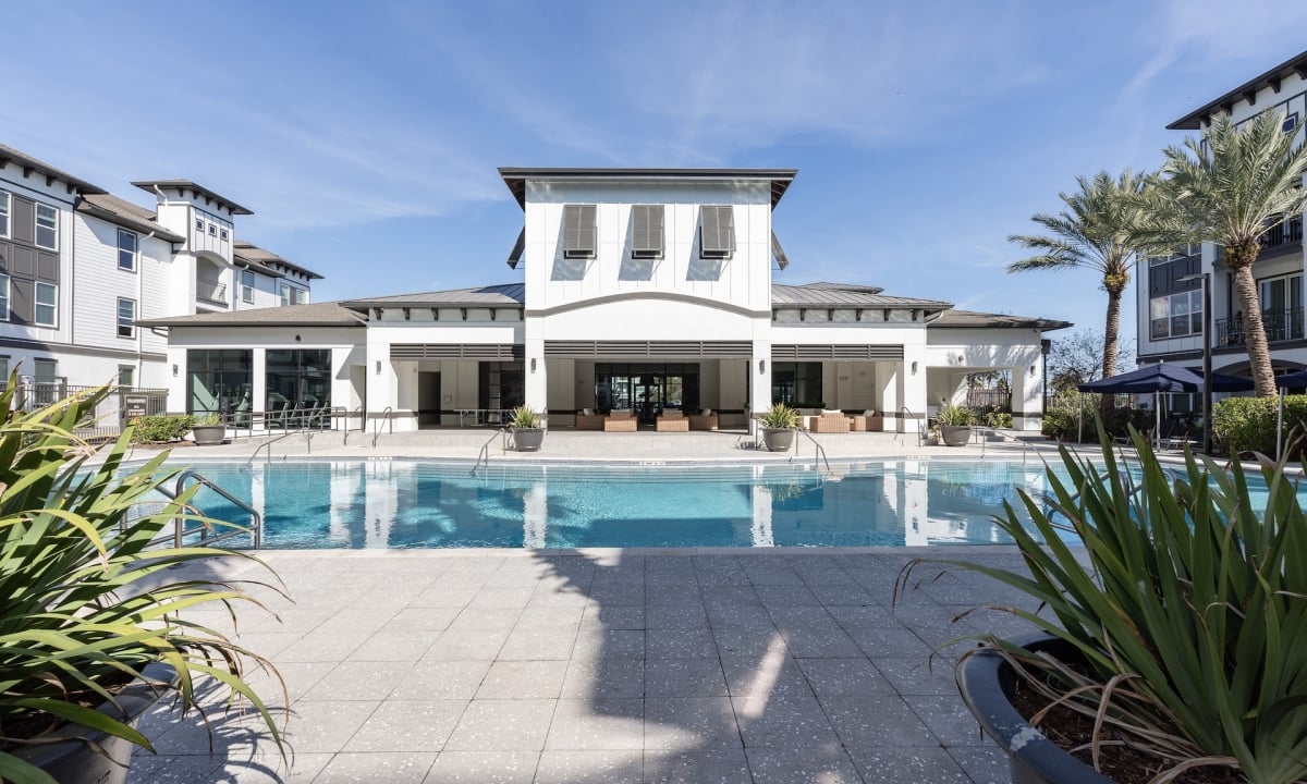A large white building with a pool in front of it