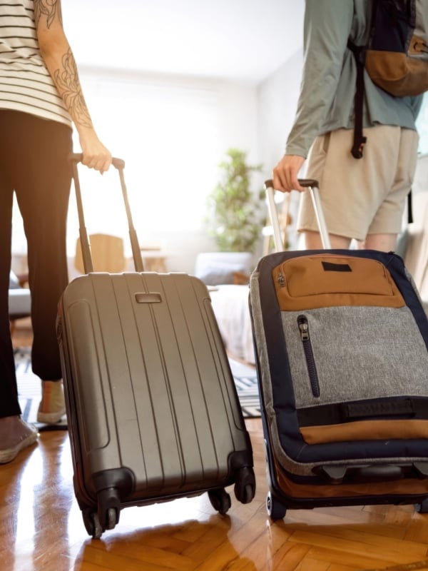 couple walking into apartment with rolling suitcases